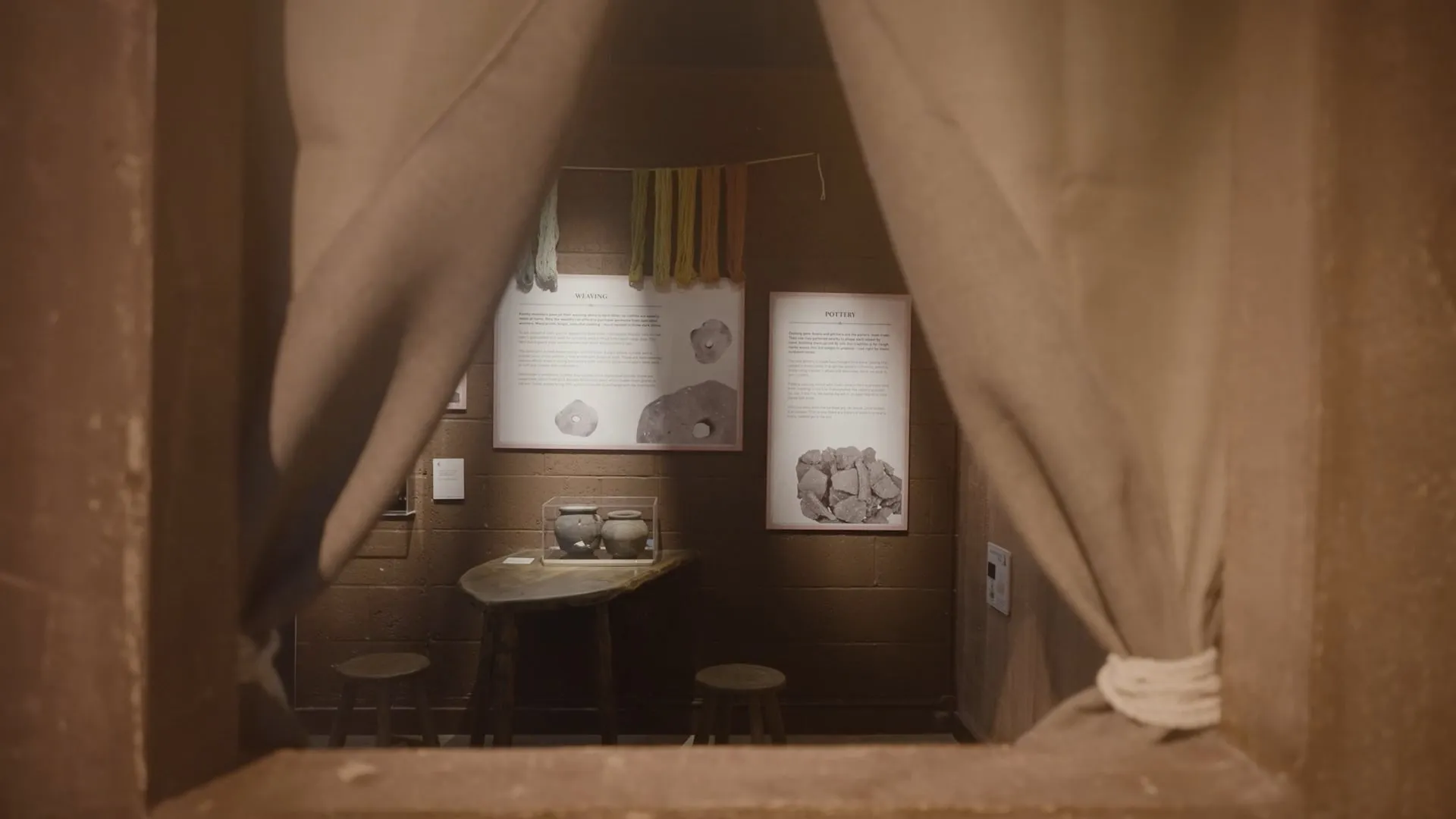 Dark curtain and a window overlooking museum exhibits of anglo saxon artifacts