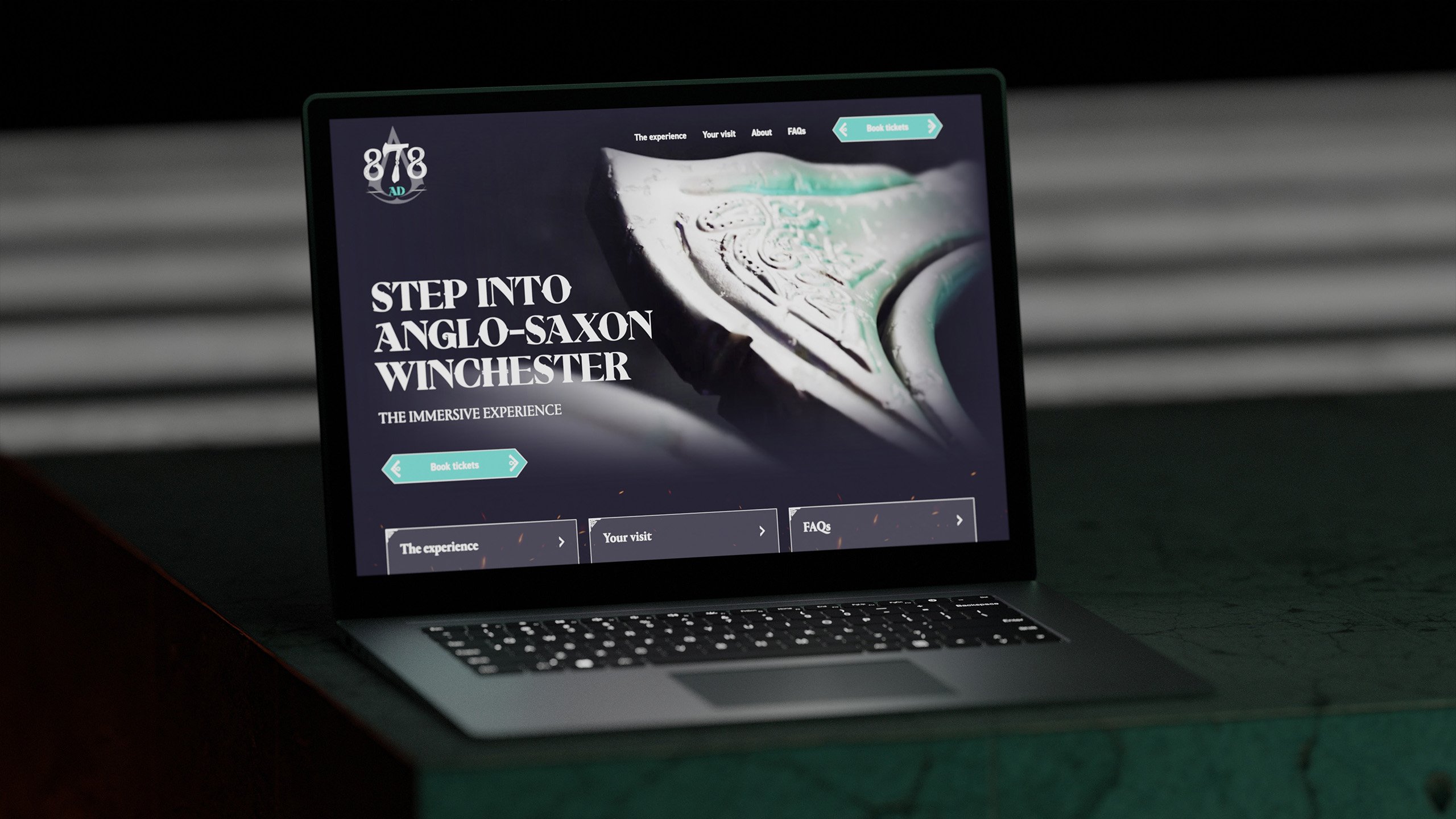 A mock up of a dark website on a laptop, the screen reads 'Step into Anglo-Saxon Winchester'