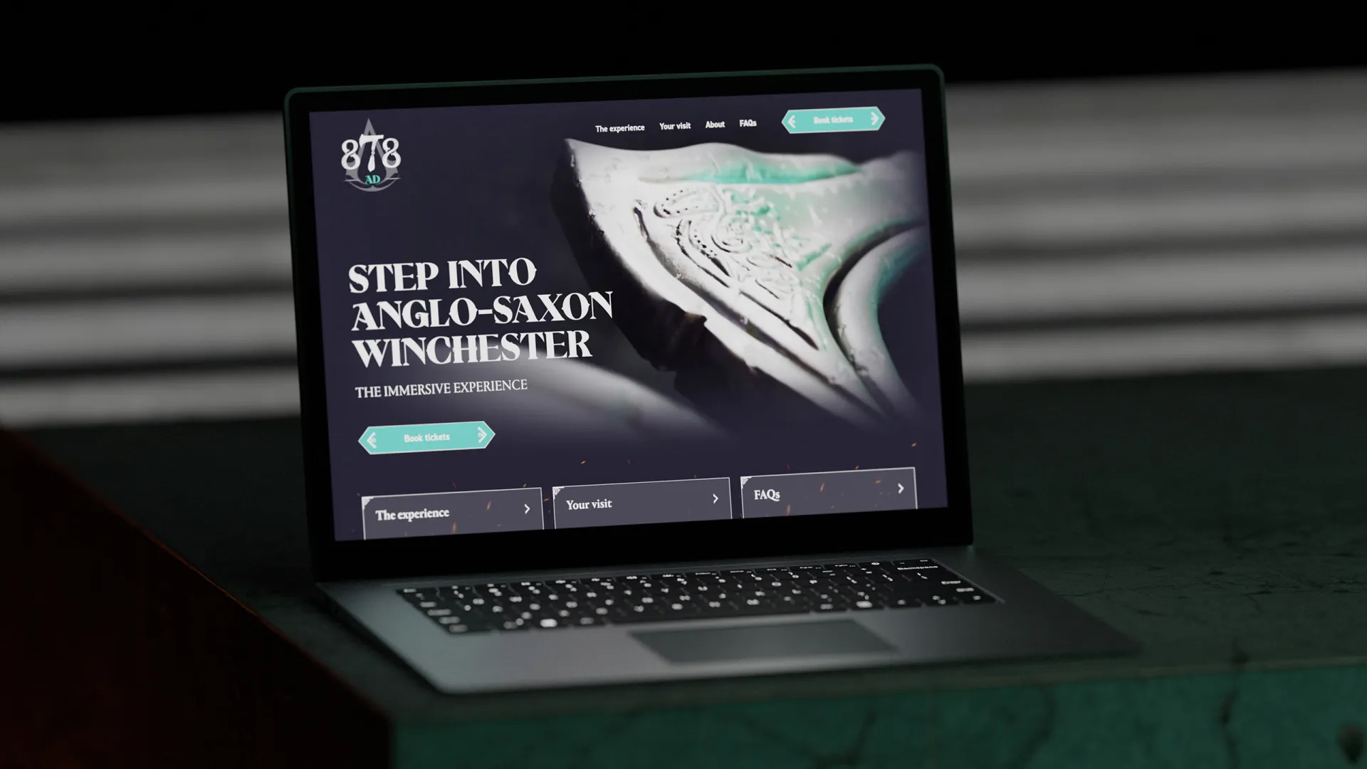 A mock up of a dark website on a laptop, the screen reads 'Step into Anglo-Saxon Winchester'
