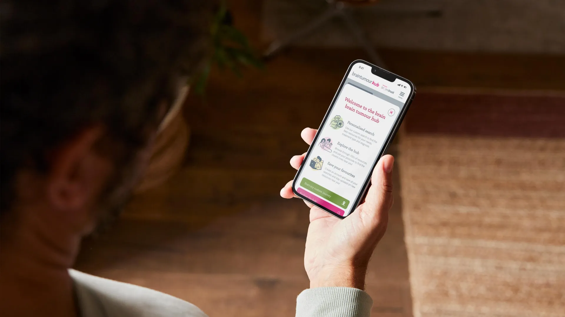 Person holding a mobile phone open on the welcome to the brain tumour hub website page.