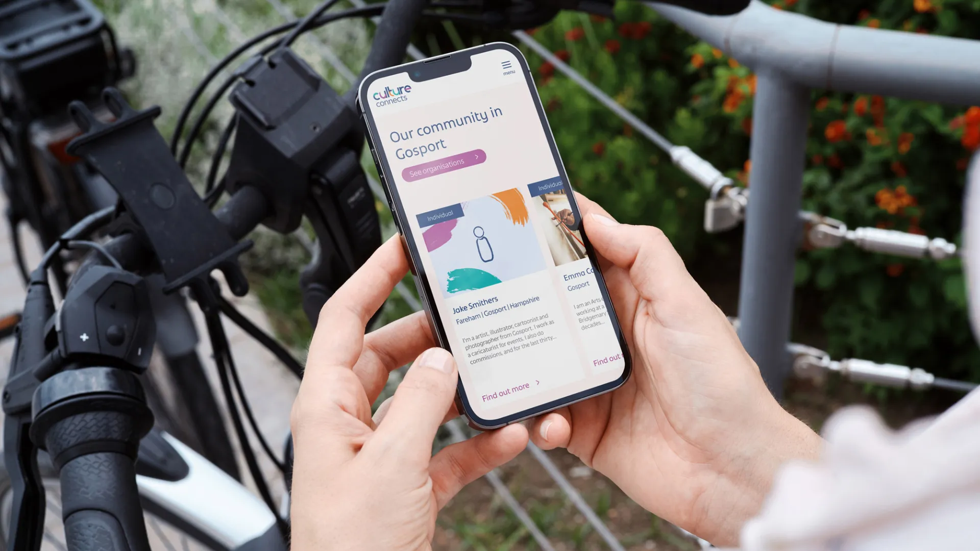 Person holding mobile phone over the top of a bicycle.