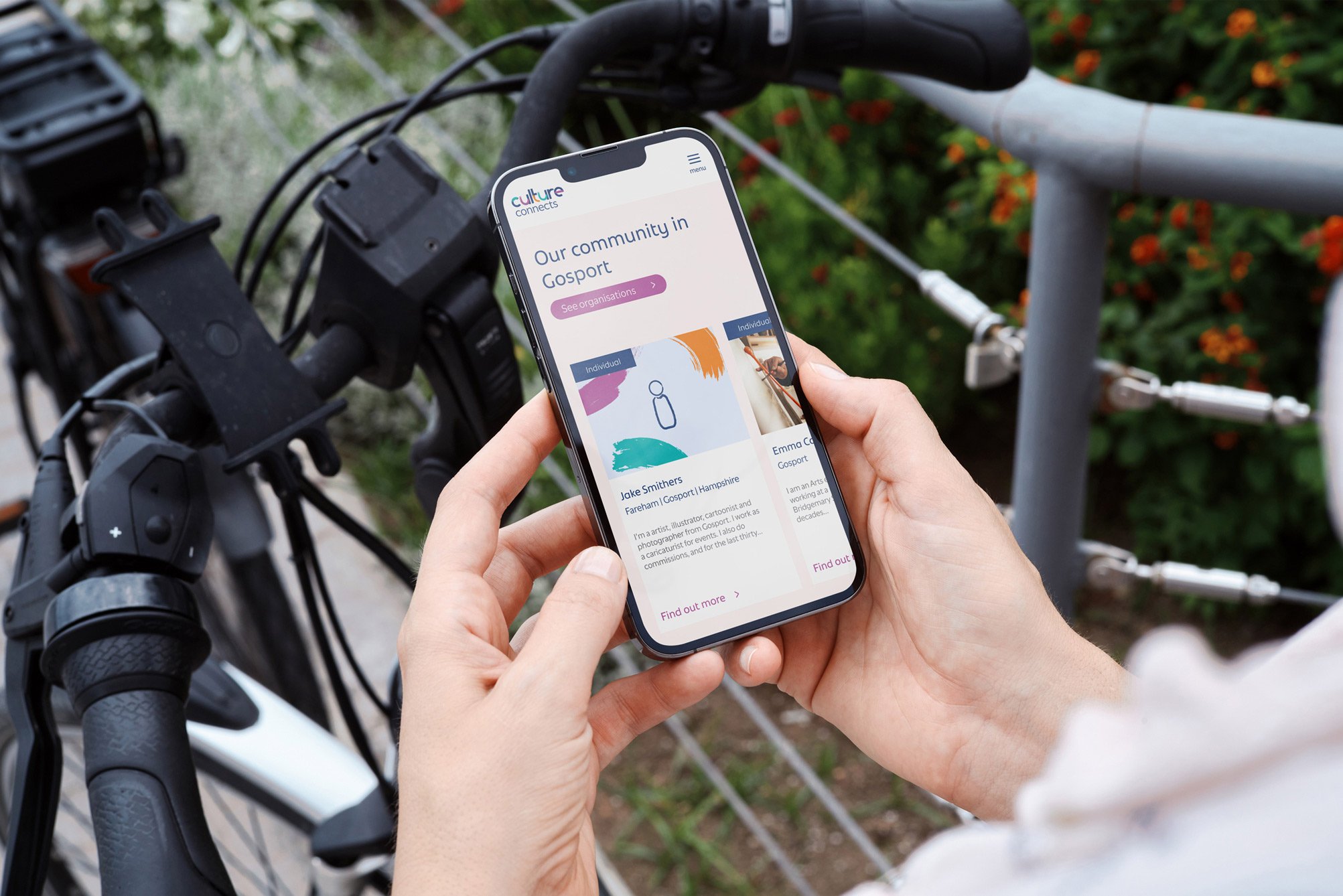 Person holding mobile phone over the top of a bicycle.