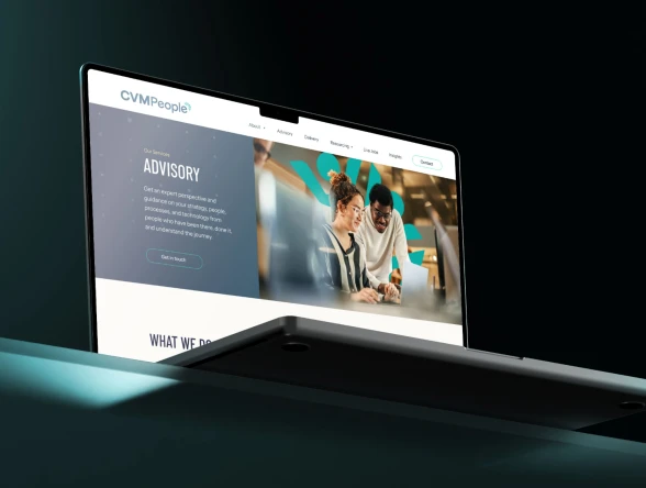 a laptop on a green table with the CVM people website on display