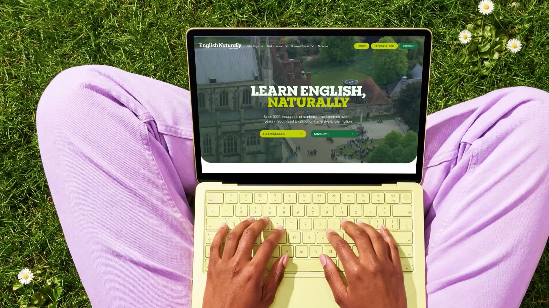 Laptop showing the English Naturally homepage while resting on grass