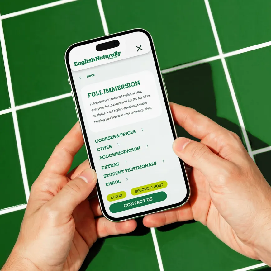 Smartphone displaying the English Naturally mobile navigation menu on a green tiled surface