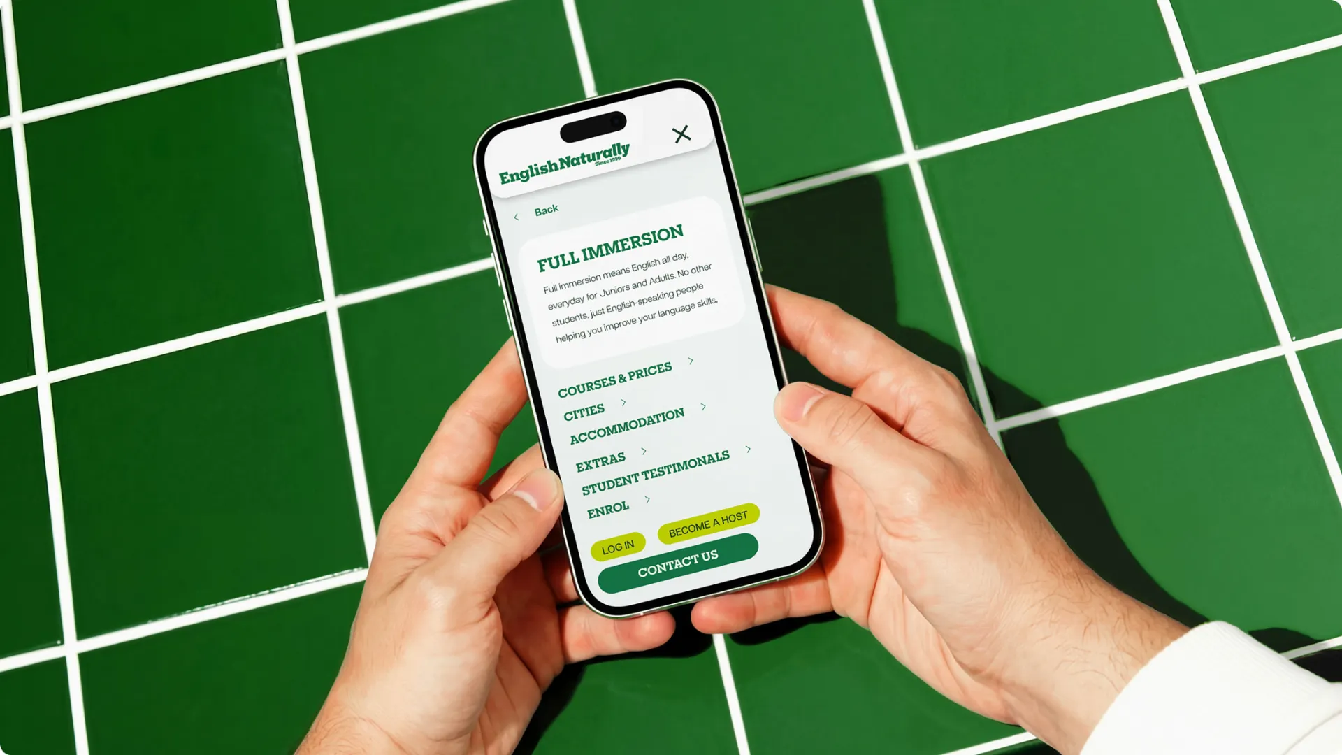 Smartphone displaying the English Naturally mobile navigation menu on a green tiled surface
