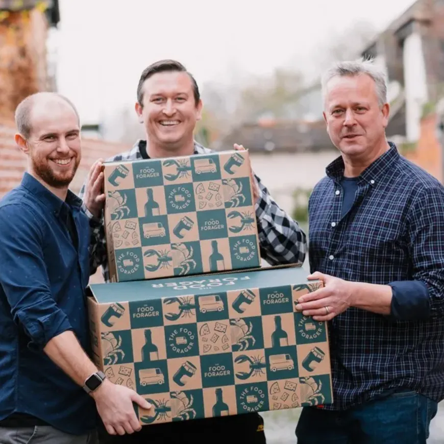 three men carrying boxes with green food forager logos