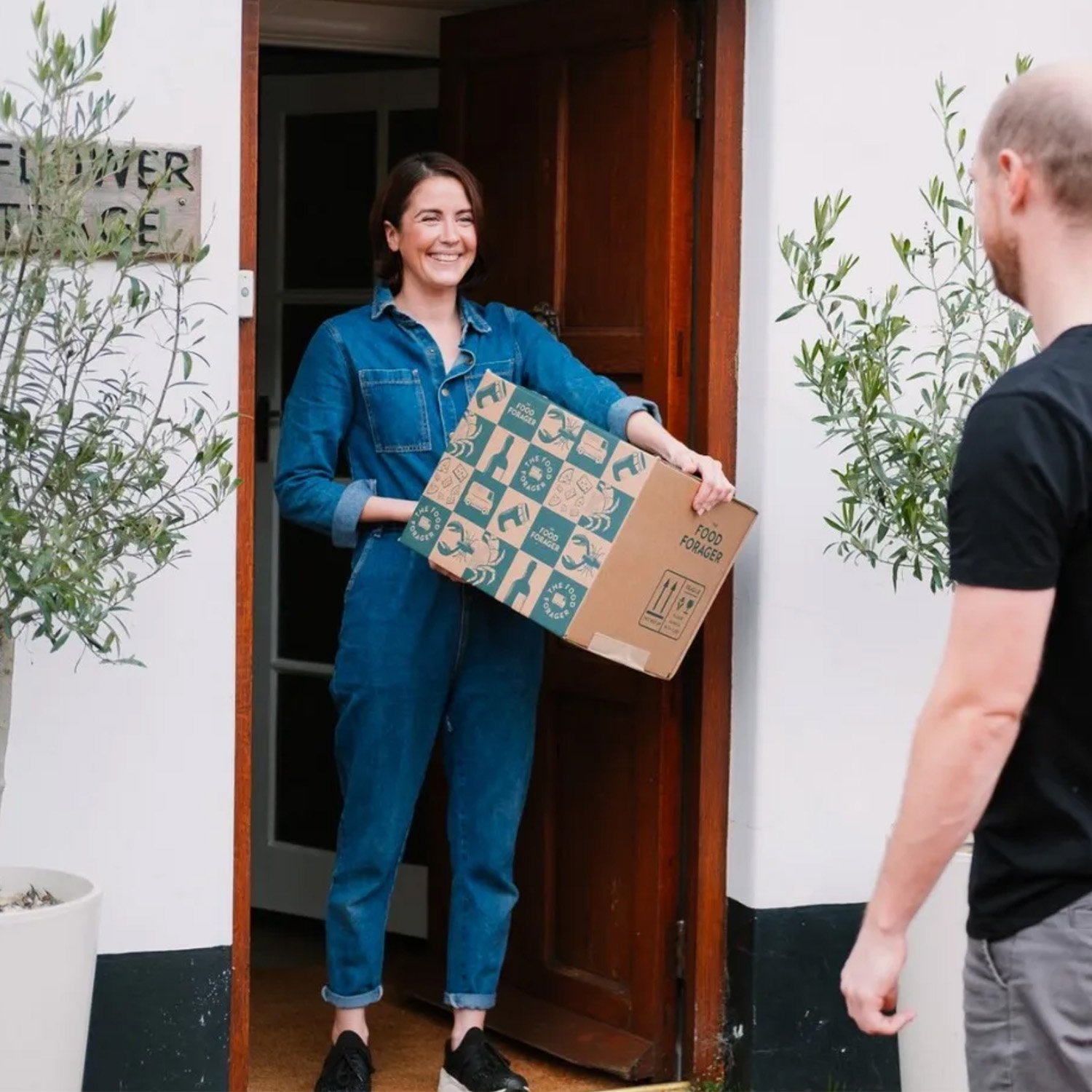 a woman at her front door receives a delivery of a food forager box