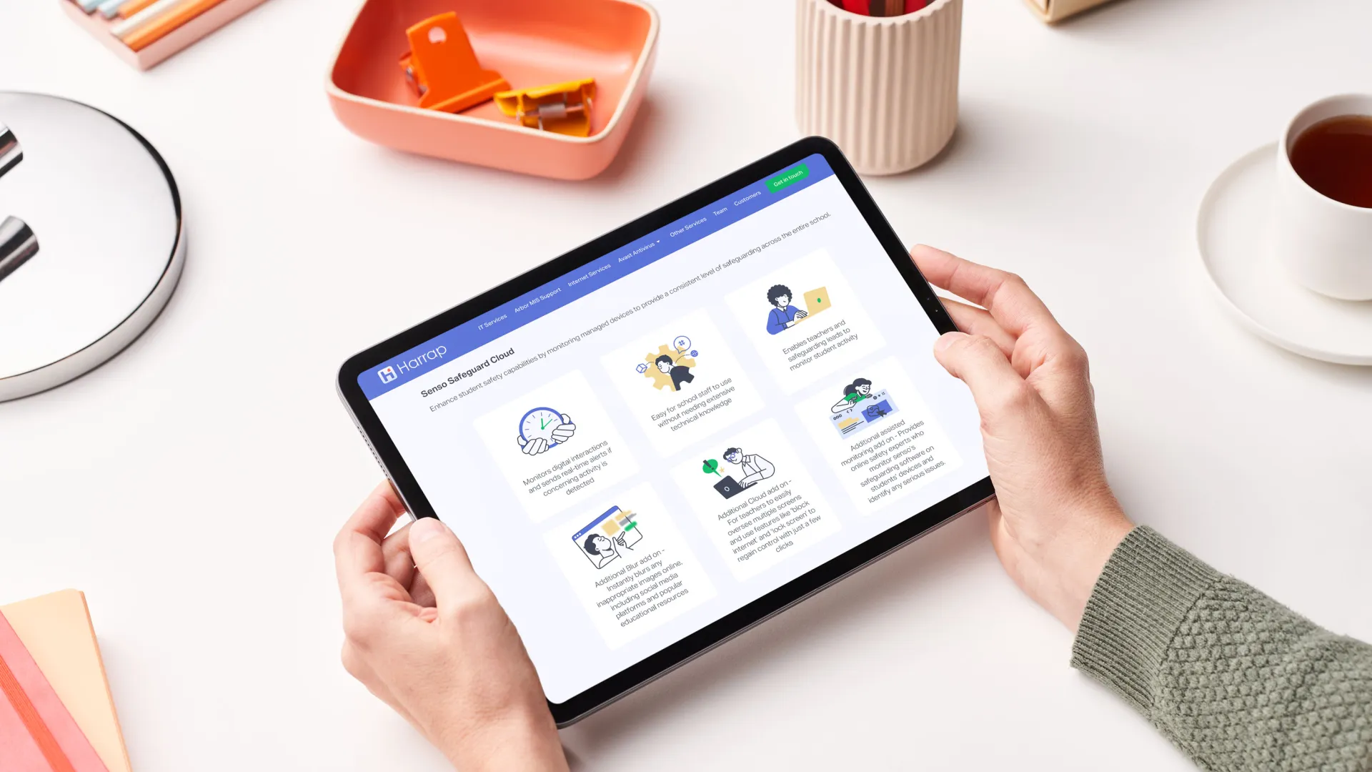 Person holding a tablet device with the Harrap website displaying
