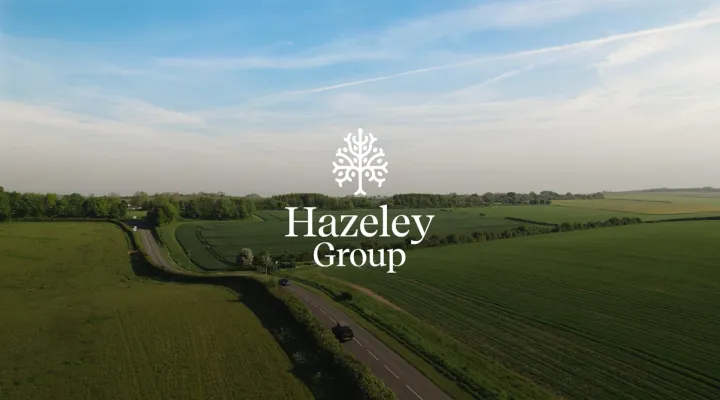 Aerial view of green countryside with the Hazeley Group logo centred over a winding rural road