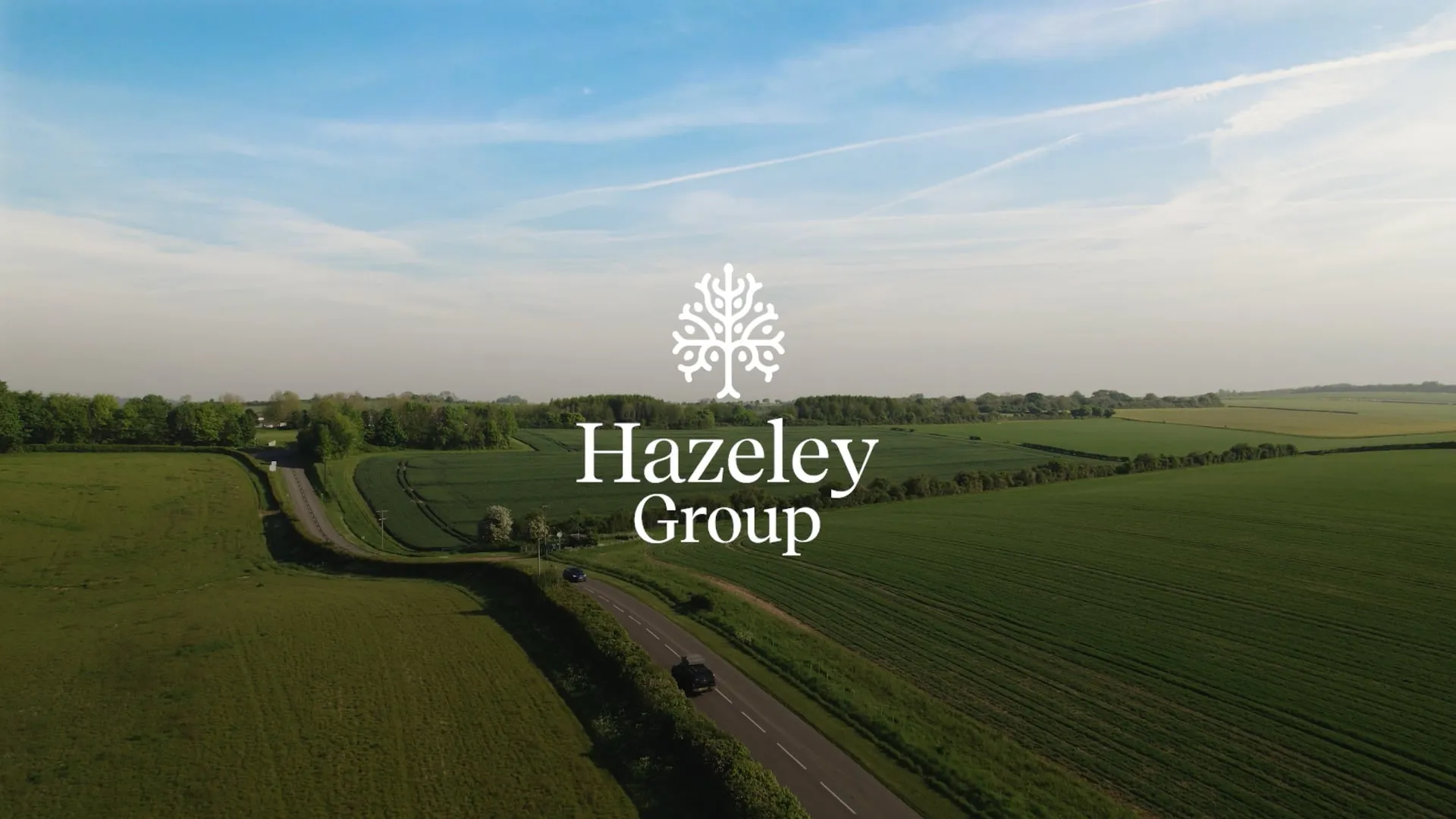 Aerial view of green countryside with the Hazeley Group logo centred over a winding rural road