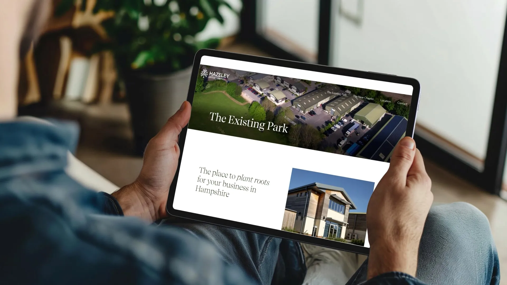 Person using a tablet to browse the Hazeley Enterprise Park website featuring aerial views and business premises in Hampshire