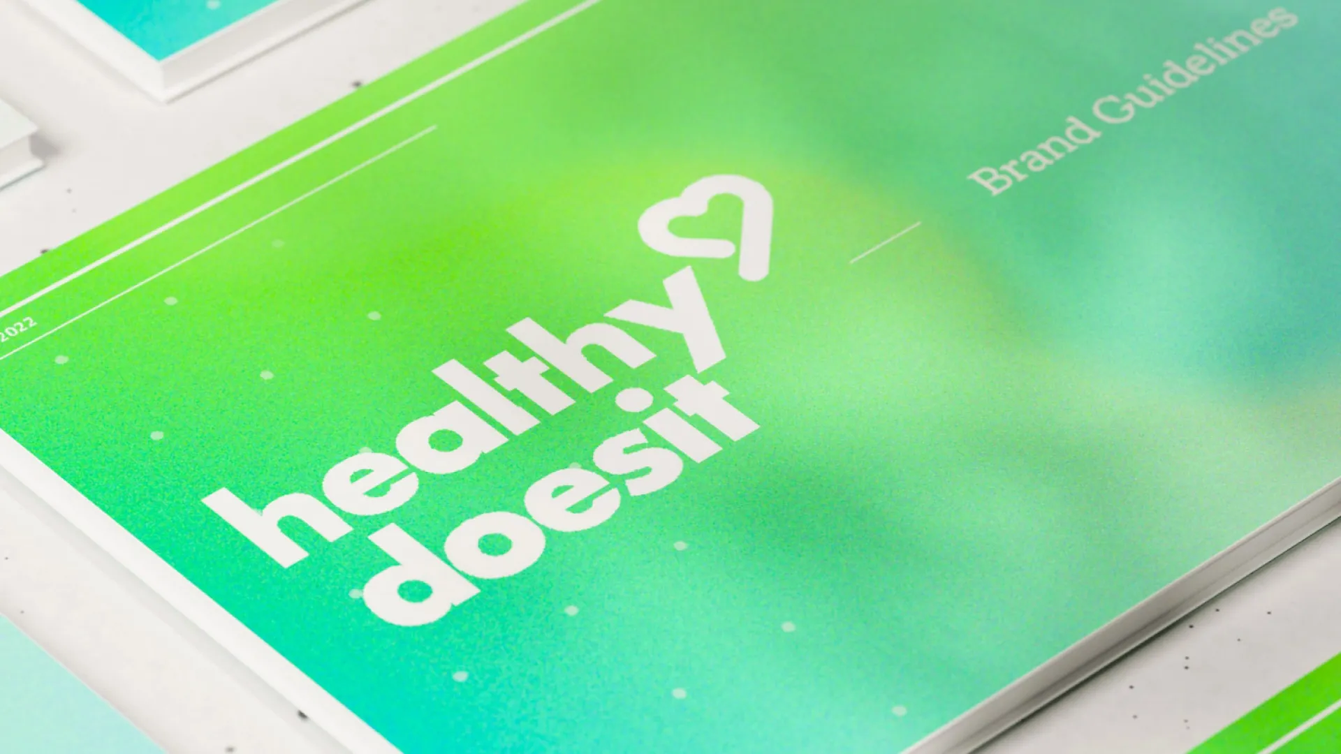 Lime green gradient covered brand guidelines books laid flat.
