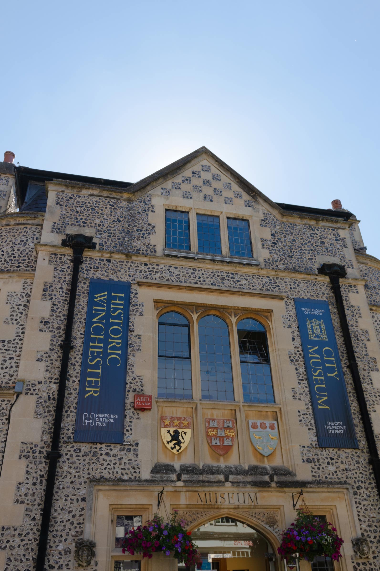 a upward view of a stone museum with two flags reading city museum and historic winchester