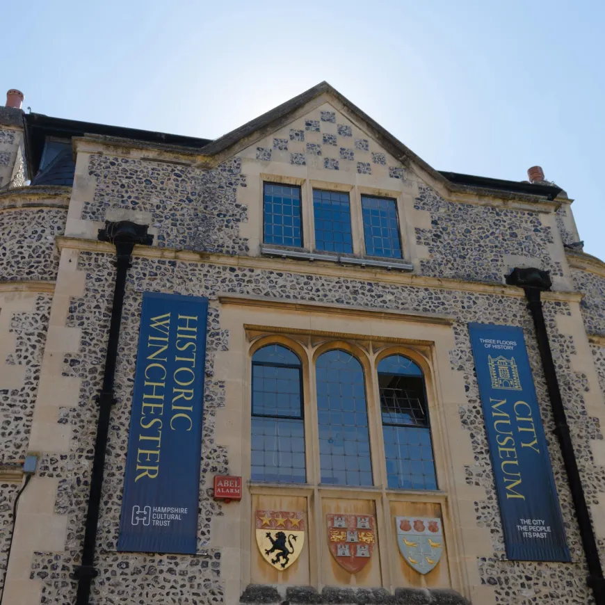 a upward view of a stone museum with two flags reading city museum and historic winchester