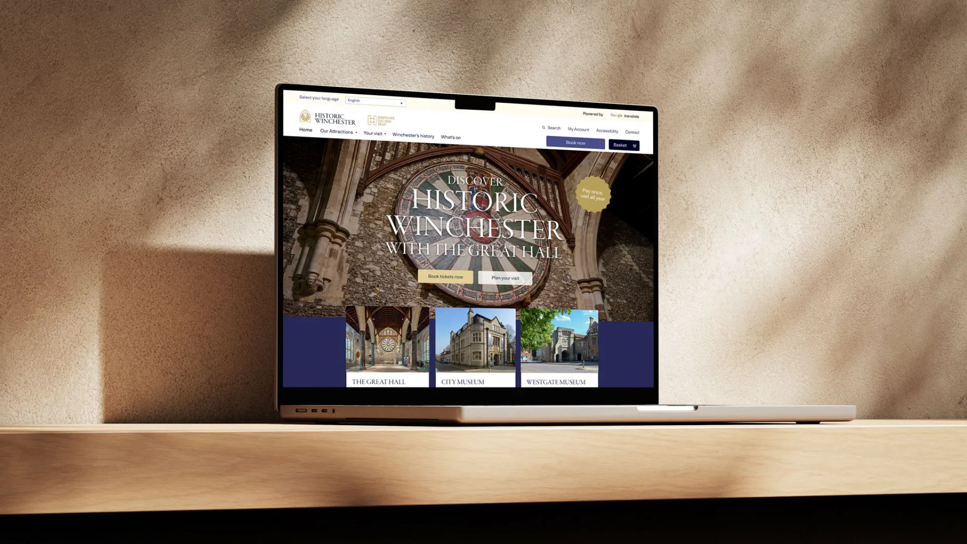 a rendering of a laptop on a pale background, on the screen is a mock up of the historic winchester website