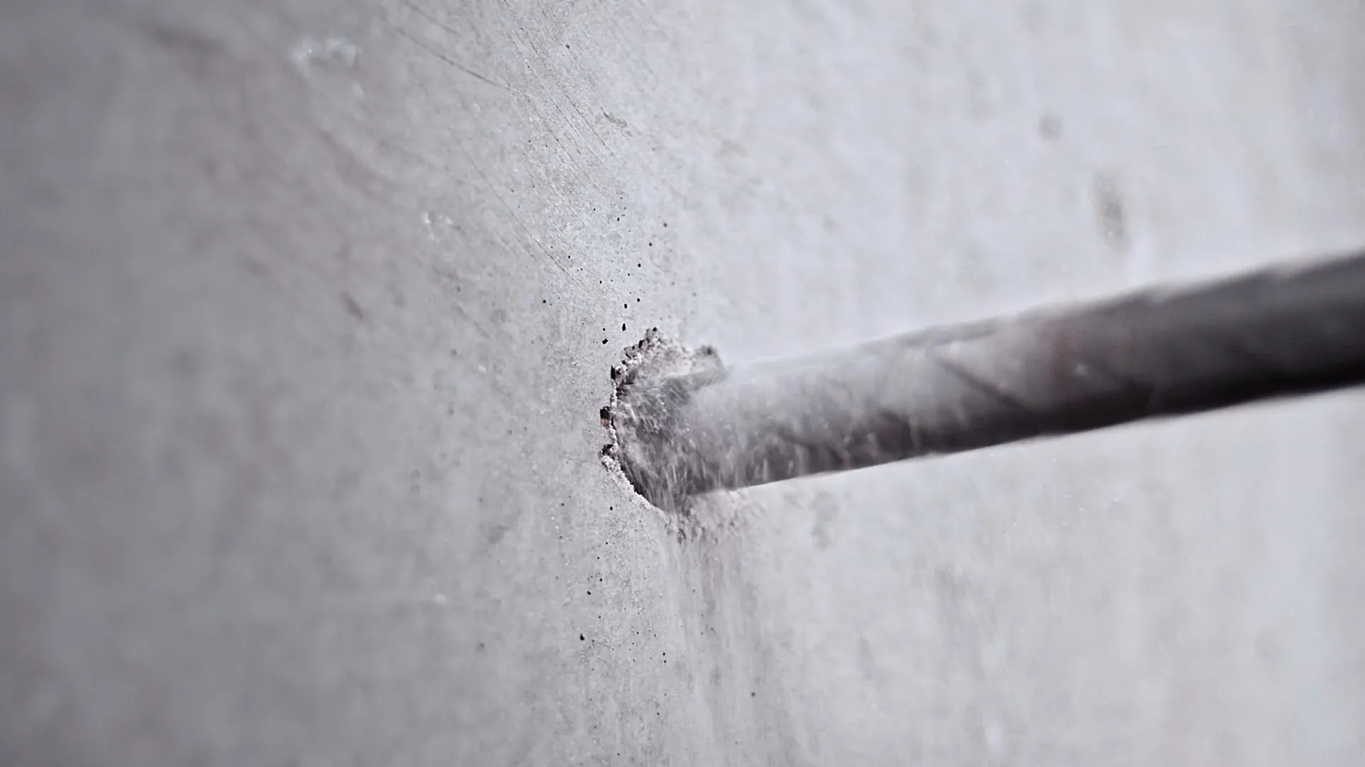 a grey wall with a drill going through it