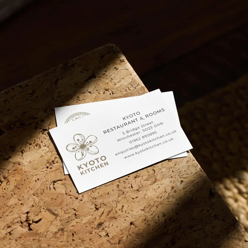 Kyoto kitchen and Bangkok bistro business cards on a cork surface.