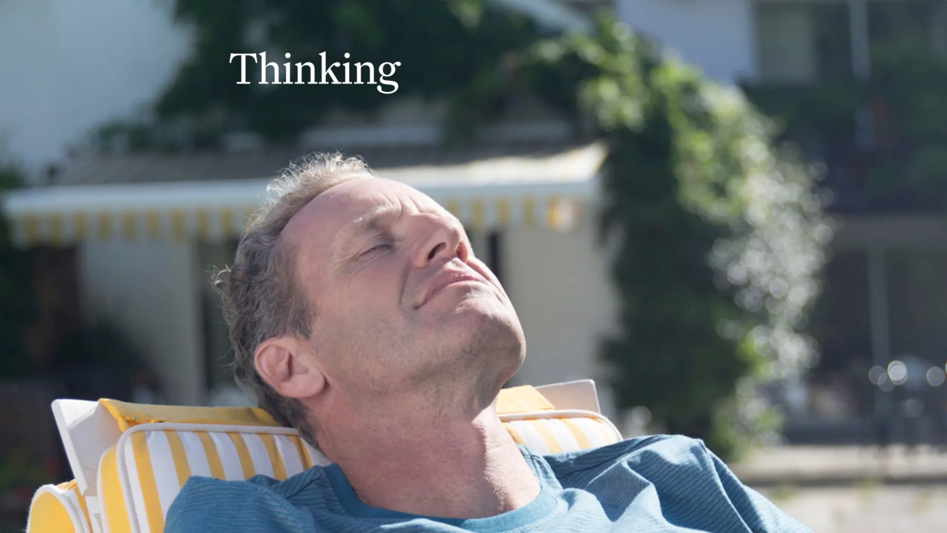 Man reclining outdoors with eyes closed in thought, with the word 'Thinking' displayed above him