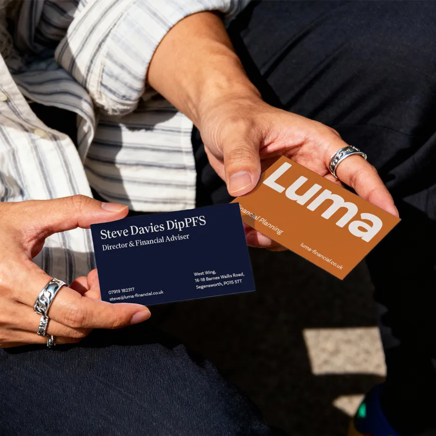 Person holding Luma Financial Planning business cards featuring the company's branding and contact details
