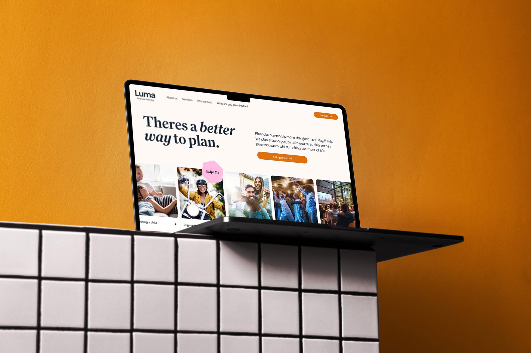 Laptop perched on the edge of a white tiled shelf against an orange background.