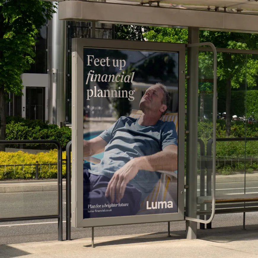 Luma Financial Planning advertisement displayed at a bus shelter featuring a person relaxing outdoors and the message "Feet up financial planning."