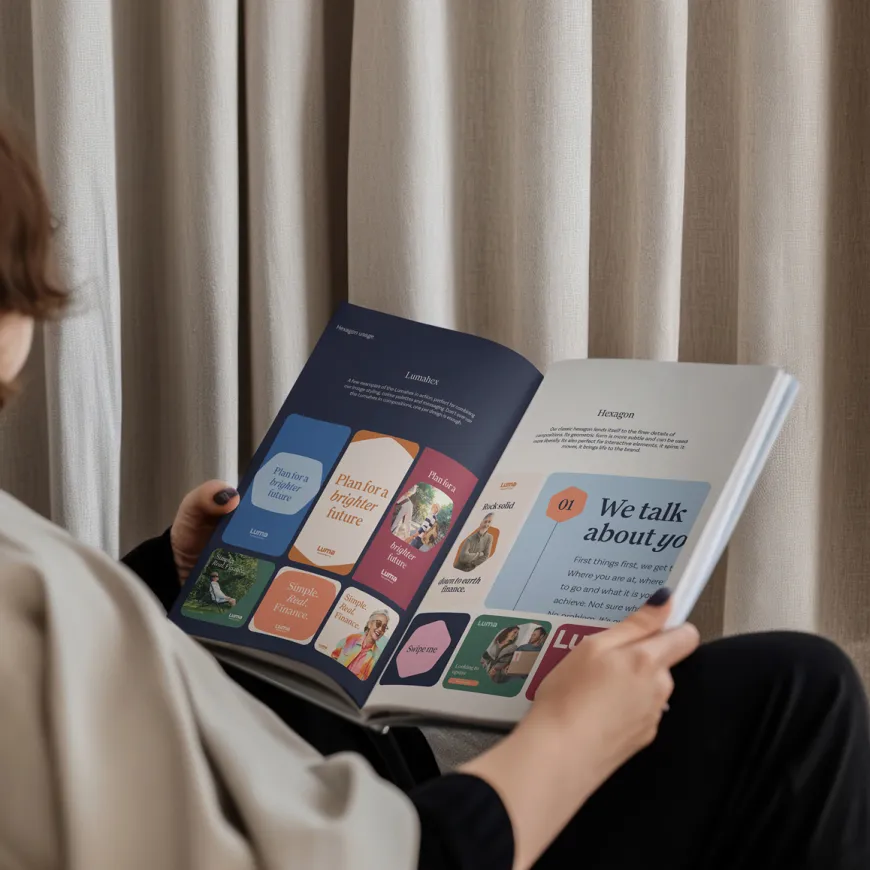 Person reading an open Luma brand publication featuring examples of the company's visual identity and messaging