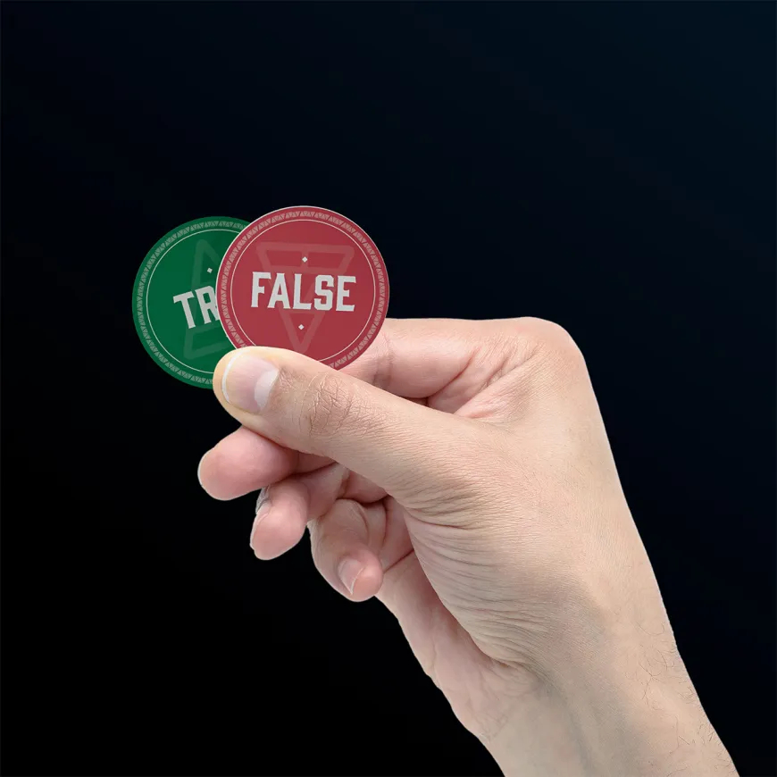 Hand holding two tokens one stating true and one labelled false