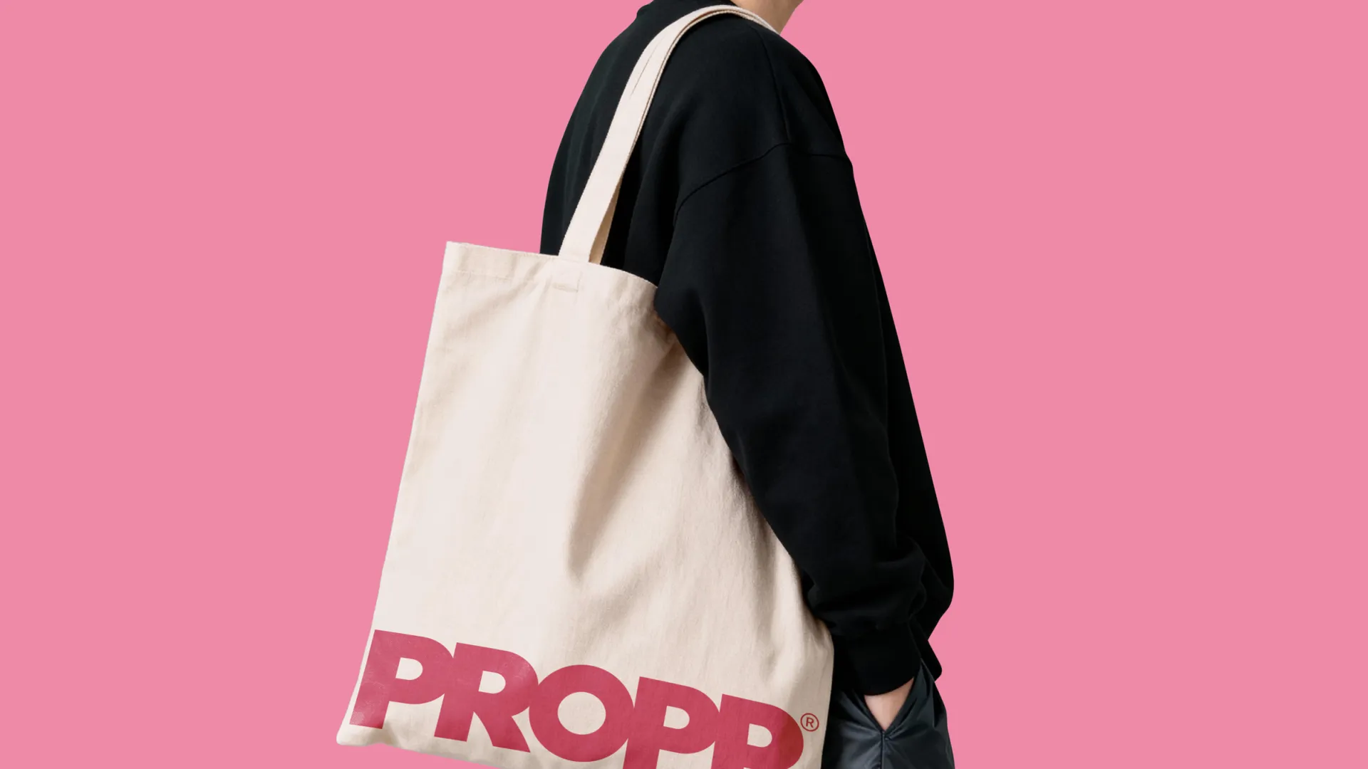 Person wearing tote bag against pink background