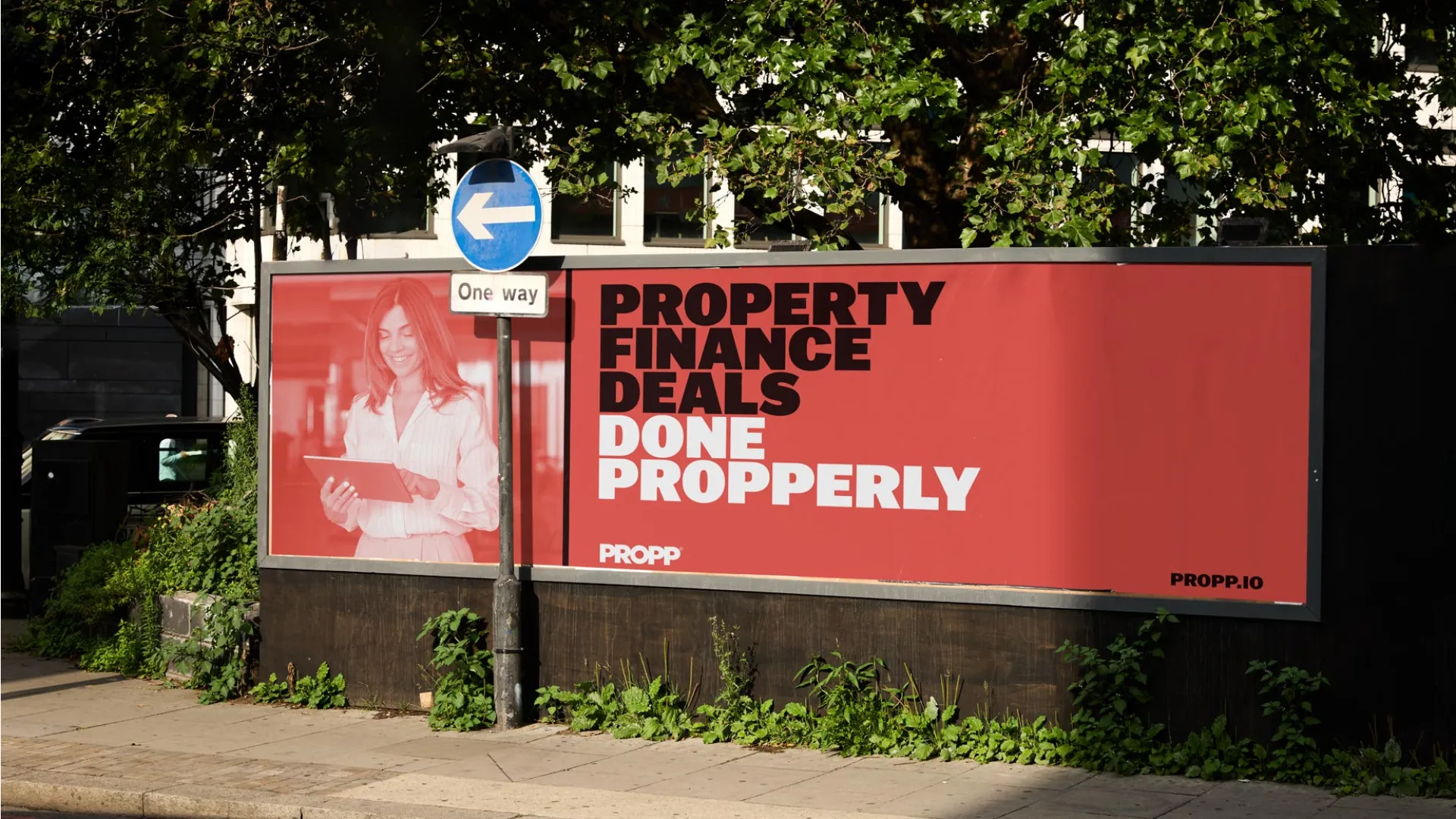 Bright red billboard on street against trees