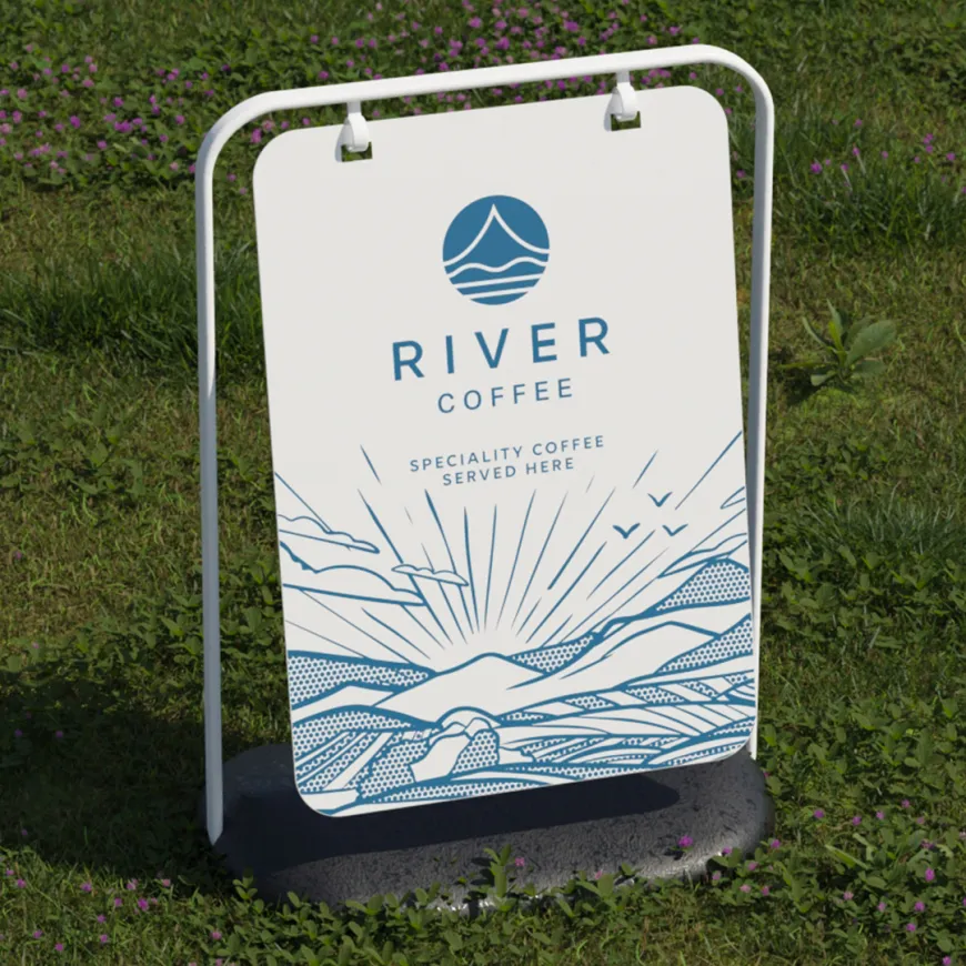 a white a board on green grass featuring river coffee branding