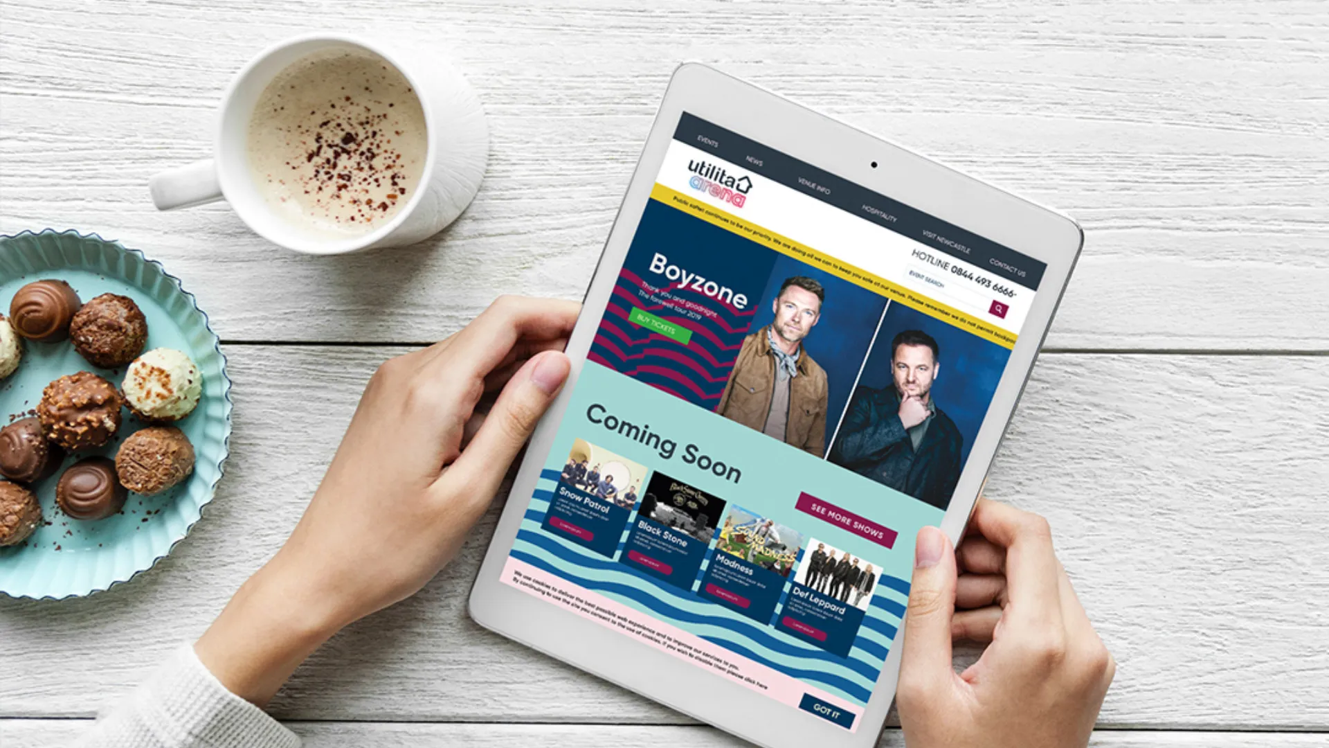 Tablet mockup of Utilita website, on wooden surface with chocolates and coffee.