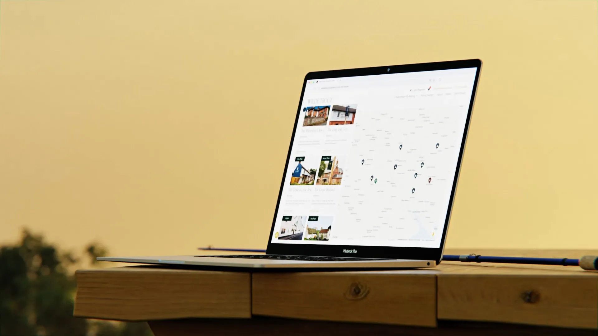Laptop mockup with Wilde Trout map page open on wooden table, yellow background.
