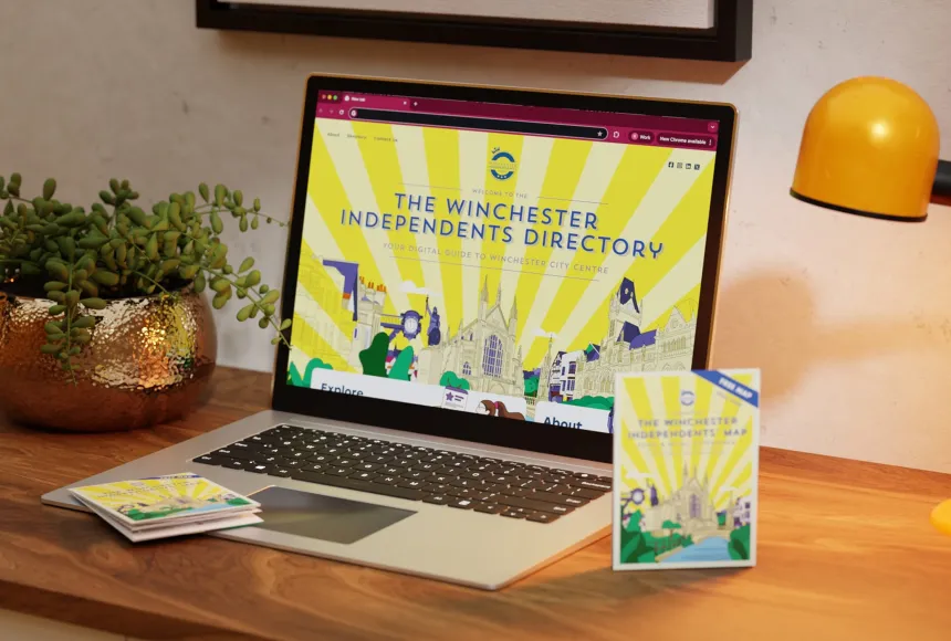 Laptop mockup displaying the Winchester Independents directory and map laid on table next to it.