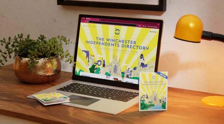Laptop mockup displaying the Winchester Independents directory and map laid on table next to it.